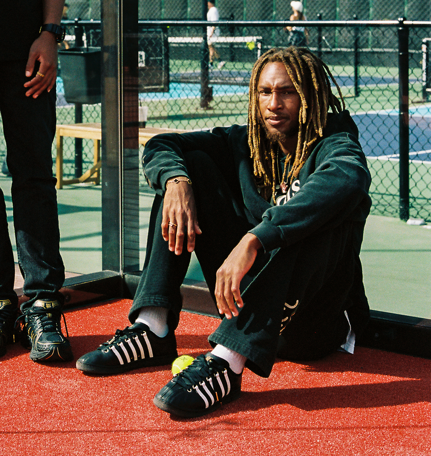 Anwar sitting in tennis court with before the classic ksrc shoe